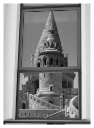 Modern building window reflecting Fisherman's Bastion in Budapest